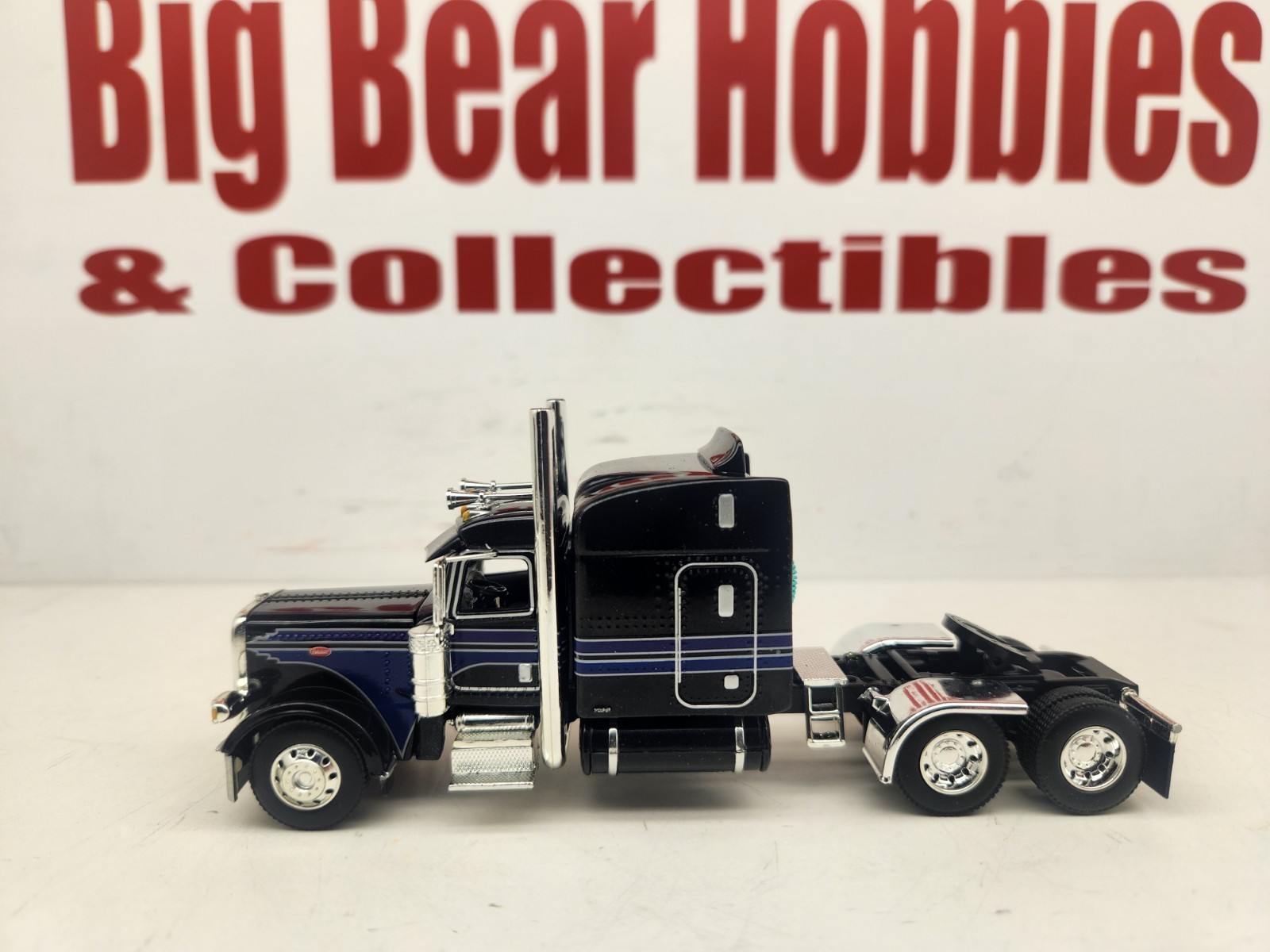 DCP 1/64 Black & Blue Graphics Peterbilt 389 63″ Midroof Sleeper Tractor