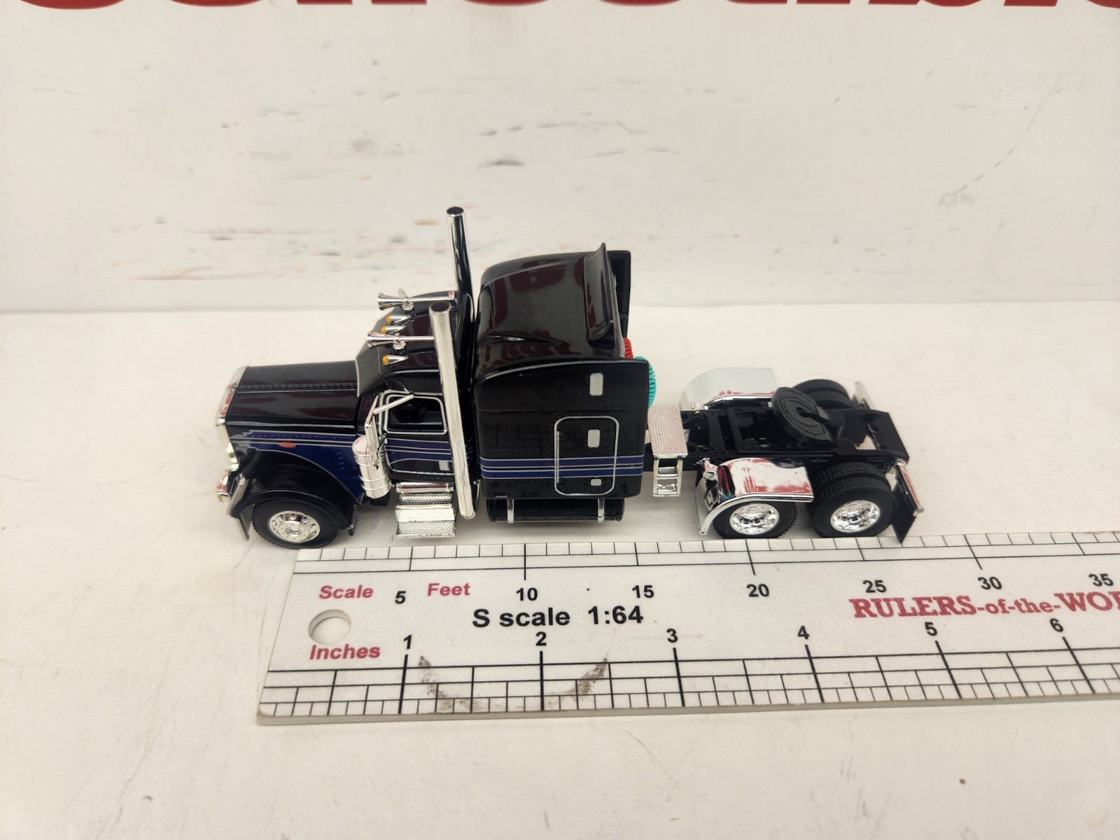 DCP 1/64 Black & Blue Graphics Peterbilt 389 63″ Midroof Sleeper Tractor