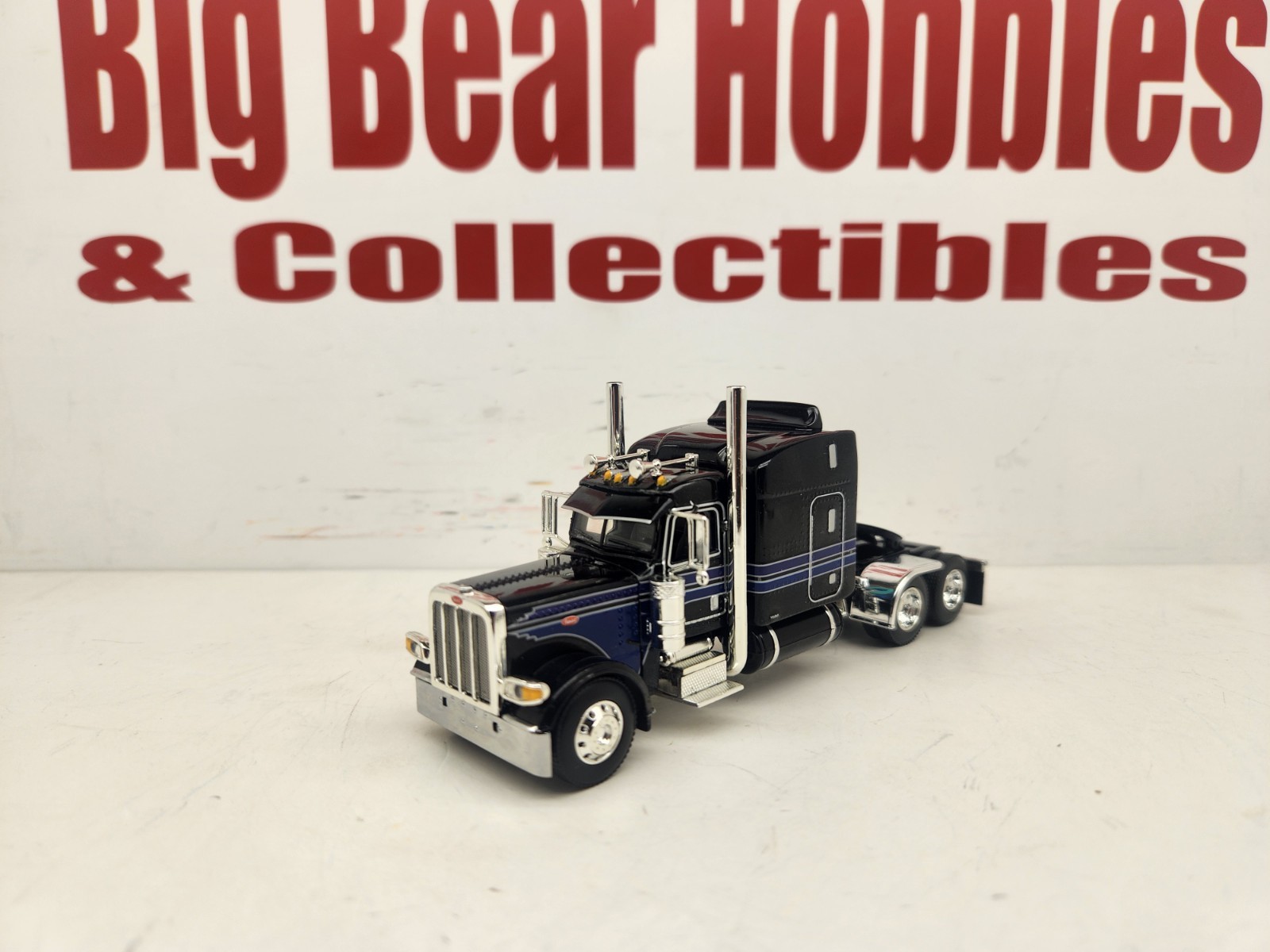 DCP 1/64 Black & Blue Graphics Peterbilt 389 63″ Midroof Sleeper Tractor