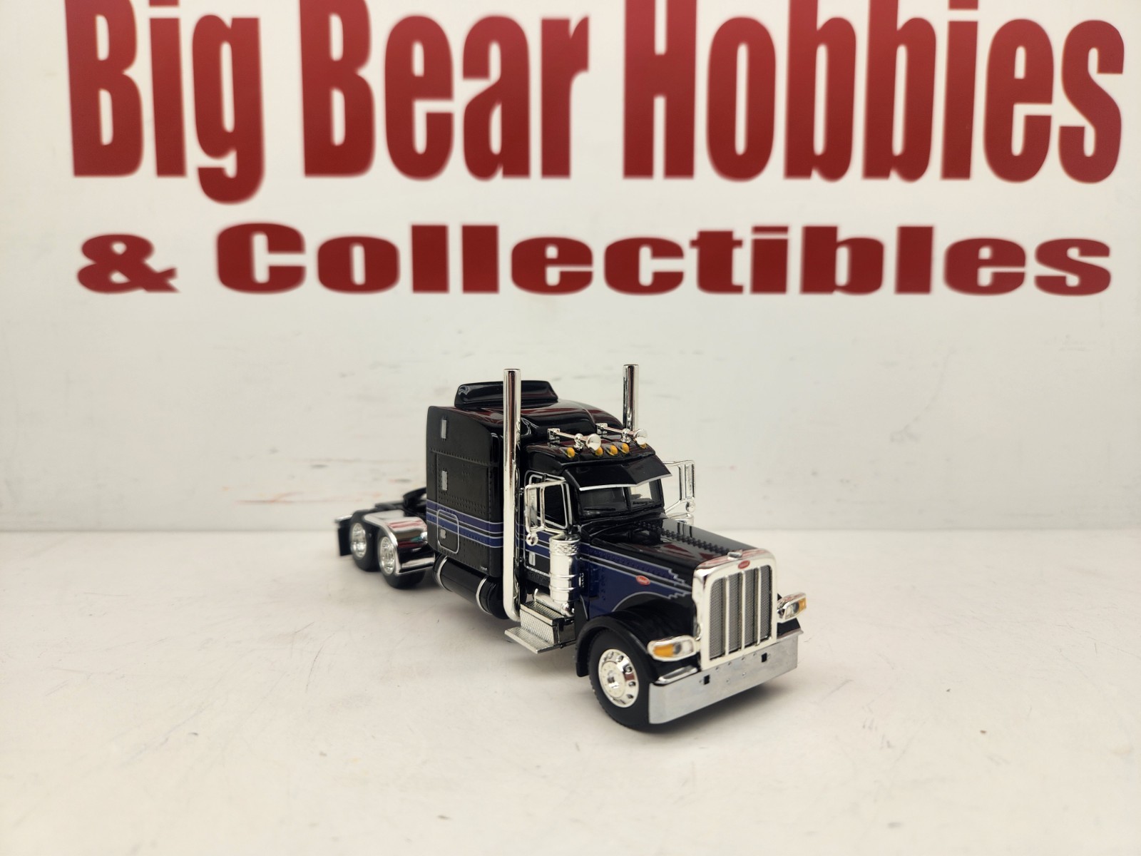 DCP 1/64 Black & Blue Graphics Peterbilt 389 63″ Midroof Sleeper Tractor