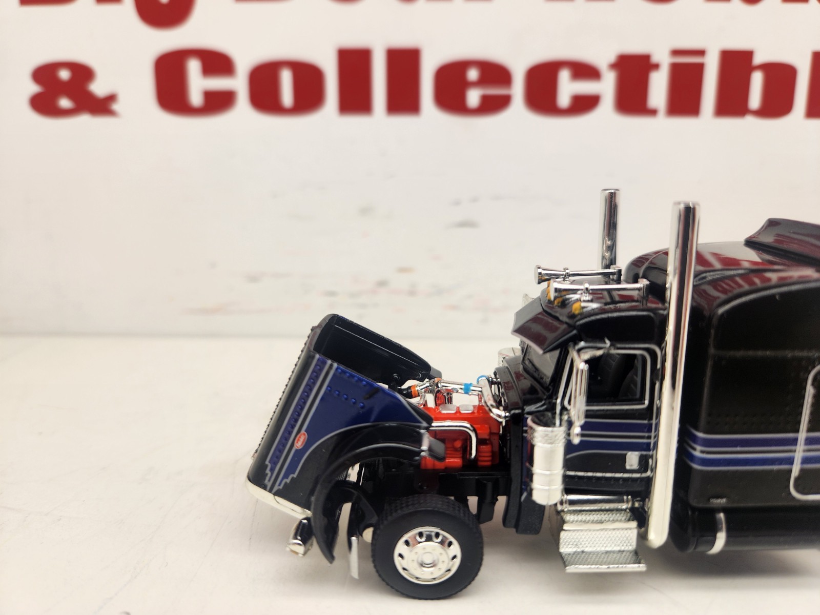 DCP 1/64 Black & Blue Graphics Peterbilt 389 63″ Midroof Sleeper Tractor